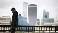 The City of London financial district is seen as a man wearing a protective face mask walks along the River Thames, amid the coronavirus disease (COVID-19) pandemic in London, Britain, July 27, 2021. REUTERS/Henry Nicholls