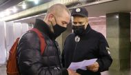 A police officer checks a certificate of vaccination against the coronavirus disease (COVID-19) or a negative COVID-19 test of a passenger at a subway station, after new restrictions were imposed by local authorities to curb the spread of the coronavirus disease (COVID-19), in Kyiv, Ukraine November 1, 2021. REUTERS/Valentyn Ogirenko
