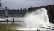 A man watches waves crash ashore where a barge that came loose from its mooring collided with the sea wall after rainstorms lashed the western Canadian province of British Columbia in Vancouver, British Columbia, Canada November 15, 2021. REUTERS/Jesse Winter
