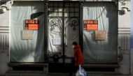 A woman wearing a protective mask due to coronavirus disease (COVID-19) pandemic walks past a closed store in central Lisbon, Portugal, November 25, 2021. REUTERS/Pedro Nunes
