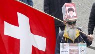 FILE PHOTO: A protestor carries a Swiss national flag during an unauthorised demonstration against COVID-19 restrictions in Zurich, Switzerland, October 30, 2021. REUTERS/Arnd WIegmann