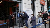 A shop employee checks customers’ vaccination certificates against the coronavirus disease (COVID-19), as the government imposed further measures for unvaccinated citizens, in Athens, Greece, November 22, 2021. REUTERS/Louiza Vradi/File Photo