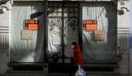 A woman wearing a protective mask due to coronavirus disease (COVID-19) pandemic walks past a closed store in central Lisbon, Portugal, November 25, 2021. REUTERS/Pedro Nunes

