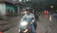 People ride a motorbike on a road that is covered with volcanic ash following an eruption of the Semeru mount volcano at Sumberwuluh village in Lumajang regency, East Java province, Indonesia, December 4, 2021, in this photo taken by Antara Foto. Antara Foto/Hermawan/via REUTERS