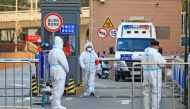 Workers in protective suits stand at an entrance to a university's residential area under lockdown following the coronavirus disease (COVID-19) outbreak in Xian, Shaanxi province, China December 20, 2021. Picture taken December 20, 2021. China Daily via REUTERS/File Photo