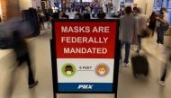 FILE PHOTO: Air travelers make their way past a sign mandating face masks for all during the outbreak of the coronavirus disease (COVID-19) at Phoenix international airport in Phoenix, Arizona, U.S. September 24, 2021. REUTERS/Mike Blake


