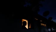 A man looks out from a window while talking to a person during the power cut in Colombo, Sri Lanka March 30, 2022. Reuters/Dinuka Liyanawatte