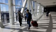 Air travellers wearing protective face masks, amid the coronavirus disease (COVID-19) pandemic, walk at JetBlue Terminal 5 at JFK International airport in New York, U.S., November 16, 2021. REUTERS/Shannon Stapleton


