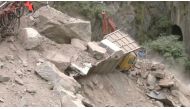 A crane removes debris from around a trapped vehicle after the collapse of a tunnel under construction in Ramban, Jammu and Kashmir, May 20, 2022, in this still image obtained from a video. ANI