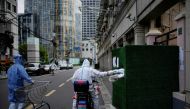 A worker in a protective suit passes food through a gap in the barrier at a residential area during lockdown, amid the coronavirus disease (COVID-19) pandemic, in Shanghai, China, May 26, 2022. REUTERS/Aly Song
