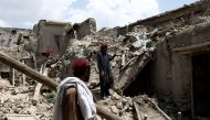 Afghan men stand on the debris of a house that was destroyed by an earthquake in Gayan, Afghanistan, June 23, 2022. (REUTERS/Ali Khara)