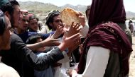 Afghan men receive bread in an area affected by an earthquake in Gayan, Afghanistan, June 23, 2022. (Reuters/Ali Khara)
 