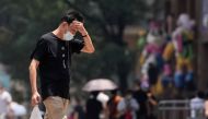 A man wearing face mask reacts on a street amid a heatwave warning, following the coronavirus disease (COVID-19) outbreak in Shanghai, China July 13, 2022. REUTERS/Aly Song