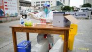 A medical worker in a protective suit sits with ice blocks at a nucleic acid testing site during preparations to test residents for the coronavirus disease (COVID-19), amid a heatwave warning in Nanchang, Jiangxi province, China July 21, 2022. China Daily via REUTERS 