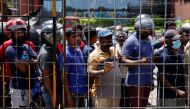 People stand behind a barbed wired gate to buy fuel at a Ceylon Petroleum Corporation fuel station, amid the country's economic crisis, in Colombo, Sri Lanka, July 26, 2022. (REUTERS/Dinuka Liyanawatte)