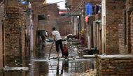 A man and a girl use a makeshift raft as they cross a flooded street, following rains during the monsoon season in Hyderabad, Pakistan, August 24, 2022. (REUTERS/Yasir Rajput)


