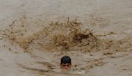 A man swims in flood waters while heading for a higher ground, following rains and floods during the monsoon season in Charsadda, Pakistan August 27, 2022. REUTERS/Fayaz Aziz