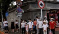 People wear face masks as they stand in a street following a coronavirus disease (COVID-19) outbreak, in Beijing, China, August 3, 2022. REUTERS/Thomas Peter/