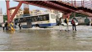 People walk next to a bus driving along a waterlogged road in Bengaluru, Karnataka state, India in this screen grab taken from a social media video September 5, 2022. Mallika Nallusamy/via REUTERS