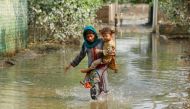 A girl carries her sibling as she walks through stranded flood water, following rains and floods during the monsoon season in Nowshera, Pakistan September 4, 2022. REUTERS/Fayaz Aziz

