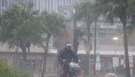 A man on a bicycle rides past in the heavy rain and wind caused by Typhoon Nanmadol in Miyazaki on Japan's southernmost main island of Kyushu September 18, 2022, in this photo taken by Kyodo. Mandatory credit Kyodo via REUTERS