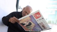 A man views a newspaper with a cover picture of Mahsa Amini, a woman who died after being arrested by the 