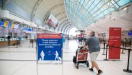 A man pushes a baggage cart wearing a mandatory face mask as a 