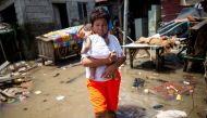 A woman carries a child as she wades through the flood caused by Super Typhoon Noru, in San Ildefonso, Bulacan province, Philippines, September 27, 2022. REUTERS/Lisa Marie David
