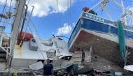 Ricky Moran stands in front of a shrimp boat, captained by him, and two other damaged boats, which were hit by Hurricane Ian at a Fort Myers Beach dock, Florida, U.S., October 5, 2022. REUTERS/Rod Nickel