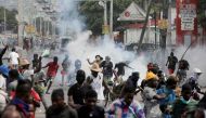 People run while police fire tear gas during a protest demanding the resignation of Haiti's Prime Minister Ariel Henry after weeks of shortages, in Port-au-Prince, Haiti, on October 10, 2022. REUTERS/Ralph Tedy Erol