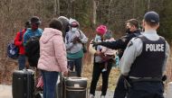Asylum seekers talk to a police officer as they cross into Canada from the US border near a checkpoint on Roxham Road near Hemmingford, Quebec, Canada, on April 24, 2022.  File Photo / Reuters
