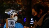 A worker in a protective suit guides people to scan health QR code at a nucleic acid test booth for the coronavirus disease (COVID-19), in Beijing, China November 11, 2022. Reuters/Tingshu Wang
