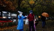 A worker in a protective suit guides people to scan health QR code at a nucleic acid test booth for the coronavirus disease (COVID-19), in Beijing, China November 11, 2022. (REUTERS/Tingshu Wang)