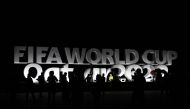 People relax in front of a FIFA World Cup sign on the Doha Corniche on November 13, 2022. (REUTERS/Hannah Mckay)