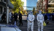 Health workers are seen near a residential area under lockdown due to Covid-19 coronavirus restrictions in Beijing on November 13, 2022. (Photo by Noel CELIS / AFP)