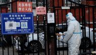 A worker in a protective suit passes a delivery good to a resident through a gate of a residential compound that is still under lockdown, following a coronavirus disease (COVID-19) outbreak, in Chaoyang District of Beijing, China, on November 26, 2022. REUTERS/Tingshu Wang