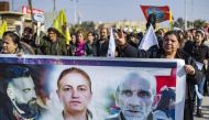 Syrian Kurds hold a banner featuring photos of three victims during a protest in Syria's northeastern city of Hasakeh on December 25, 2022 in response to a deadly attack targeting members of the ethnic community in Paris this week. Photo by Delil SOULEIMAN / AFP