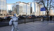 A woman wearing personal protective equipment (PPE) amid the Covid-19 pandemic walks along a street in Beijing on December 26, 2022. (Photo by Noel CELIS / AFP)