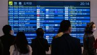 People wait in front a board showing international flight arrivals at Tokyo's Haneda international airport on December 28, 2022. Photo by Philip FONG / AFP