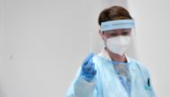 A health worker wearing personal protective equipment (PPE) holds a swab in her hand to conduct tests for the coronavirus disease (COVID-19), after Italy has ordered COVID-19 antigen swabs and virus sequencing for all travellers coming from China, where cases are surging, at the Malpensa Airport in Milan, Italy, on December 29, 2022. REUTERS/Jennifer Lorenzini