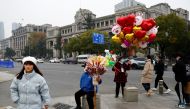 People walk past a ballon vendor, amid the coronavirus disease (Covid-19) outbreak, in Wuhan, Hubei province, China, on December 31, 2022. REUTERS/Tingshu Wang