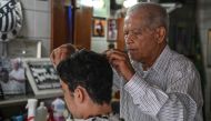 Barber Joao Araujo, known as Didi, who cut Brazilian football legend Pele's hair, works in his hairdressing salon in Santos, Brazil, on December 30, 2022.  (Photo by Nelson ALMEIDA / AFP)