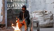 A man keeps himself warm near a fire during early morning hours along a street in Karachi, Pakistan, January 4, 2023. (REUTERS/Akhtar Soomro)