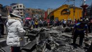 Supermarket workers inspect the fire damage in Puno, Peru, on January 10, 2023, a day after 18 people were killed in clashes between demonstrators and security forces. (Photo by Juan Carlos Cisneros / AFP)