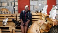 Rachael Kabue, the founder of the Nairobi Feline Sanctuary sits with the cats at the courtyard of the rescue and rehabilitation centre hosting homeless domesticated cats, in Utawala district of Nairobi, Kenya, January 12, 2023. REUTERS/Monicah Mwangi