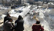 People watch as rescuers sift through the rubble of a building that collapsed in the the northern Syrian city of Aleppo on January 22, 2023.(AFP)