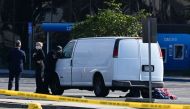 A law enforcement official looks into the window of a van with a body in the driver's seat in Torrance, California, on January 22, 2023. (Photo by Robyn Beck / AFP)