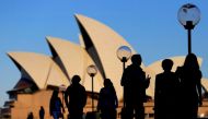 People are silhouetted against the Sydney Opera House at sunset in Australia, November 2, 2016. File Photo: REUTERS/Steven Saphore
