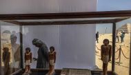 Workers stand behind a collection of pharaoh statues during a press conference at the Saqqara archaeological site, where a gold-laced mummy and four tombs including of an ancient king's 
