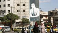 People walk near a poster depicting Syria's President Bashar al-Assad in Homs, Syria, on October 3, 2021. Picture taken October 3, 2021. File photo / Reuters